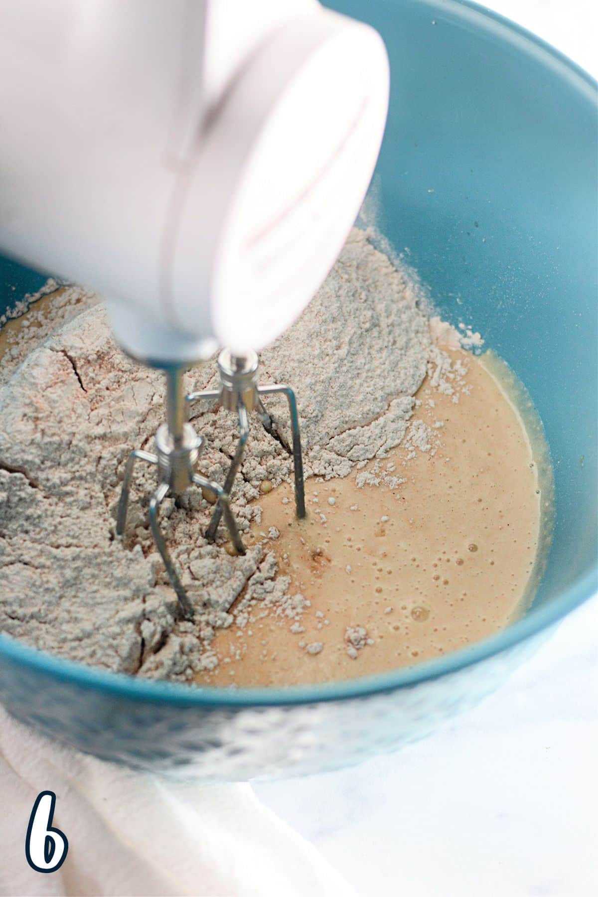 A mixer is mixing flour in a bowl to prepare Apple Cinnamon Muffins.