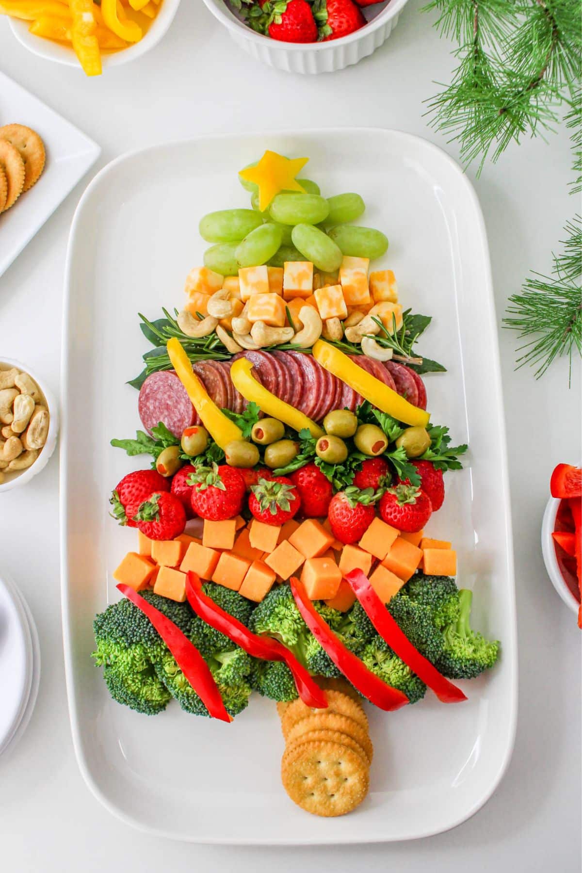 A christmas tree shaped platter with vegetables and crackers.