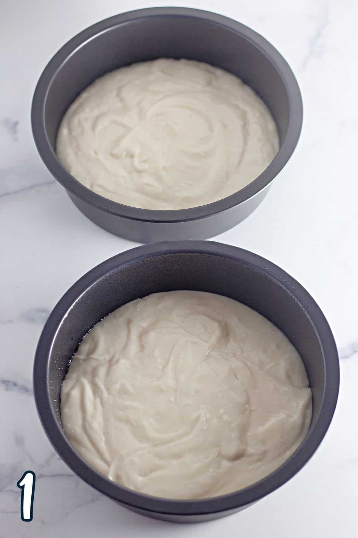 Two cake pans with white batter in them.