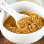 Pumpkin pie spice in a white bowl with a white spoon.