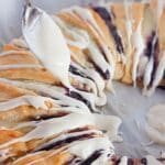 A spoon is drizzling icing on a pastry.
