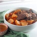 A bowl of stew with carrots and potatoes.
