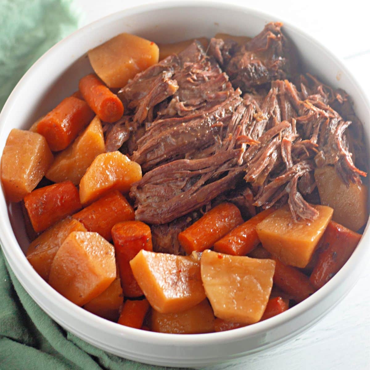 A bowl of beef stew with carrots and potatoes.