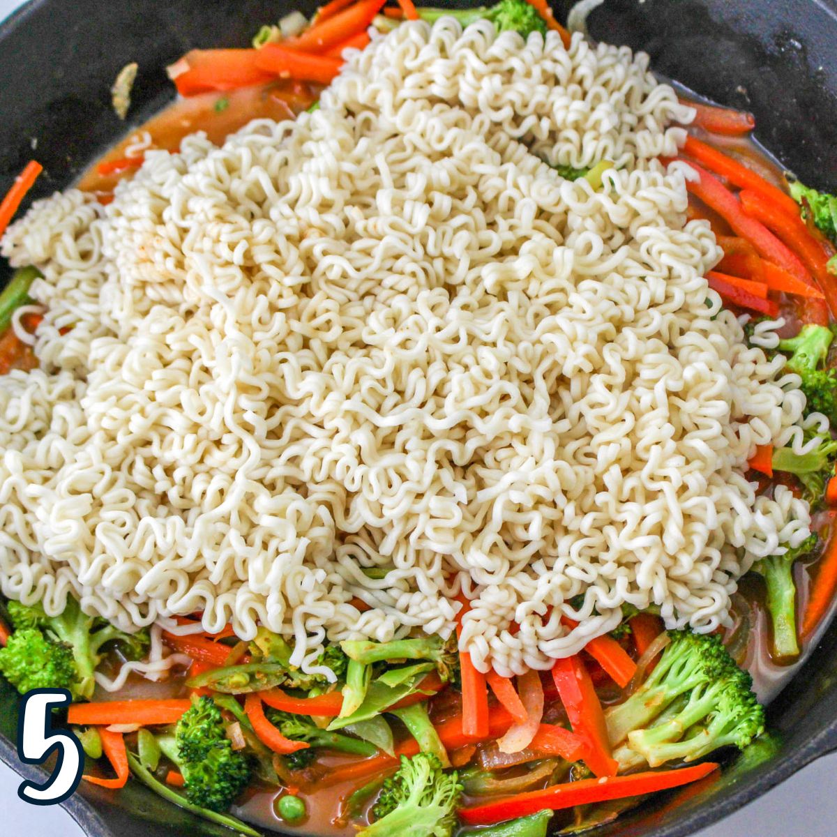 A pan with ramen noodles and vegetables in it.