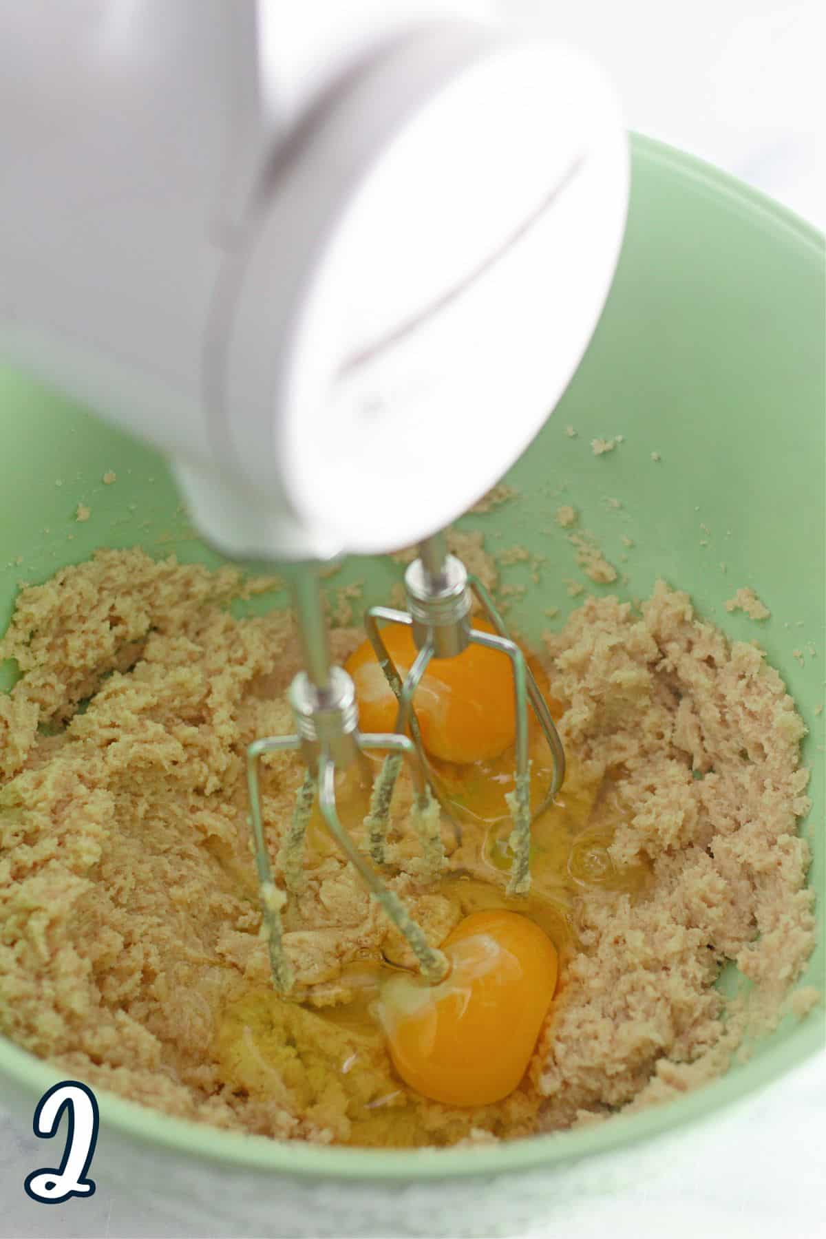 A green bowl with eggs, butter, sugar, and a hand mixer.