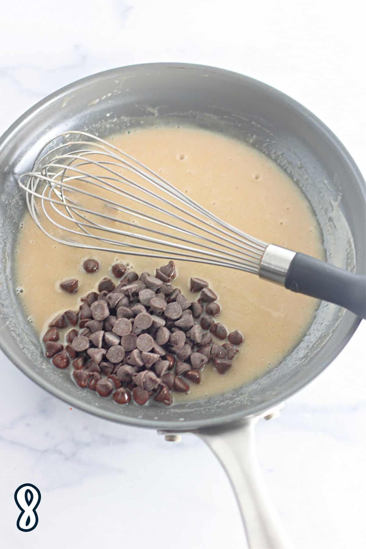 Chocolate chips in a pan with a whisk and hot sweetened cream.