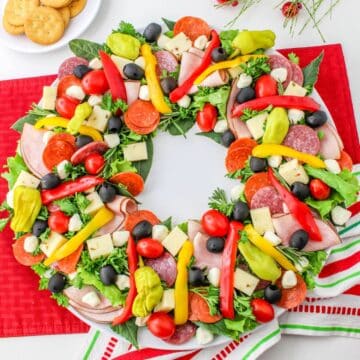 A wreath of vegetables and meats on a red napkin.