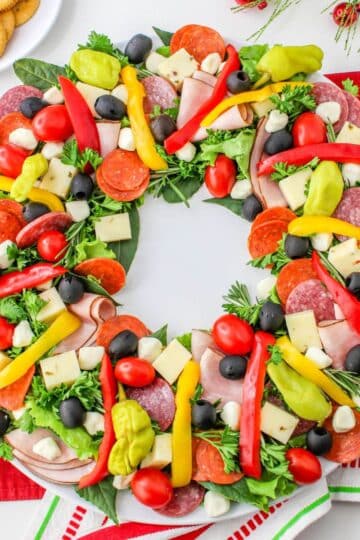 A wreath of vegetables and meats on a red napkin.