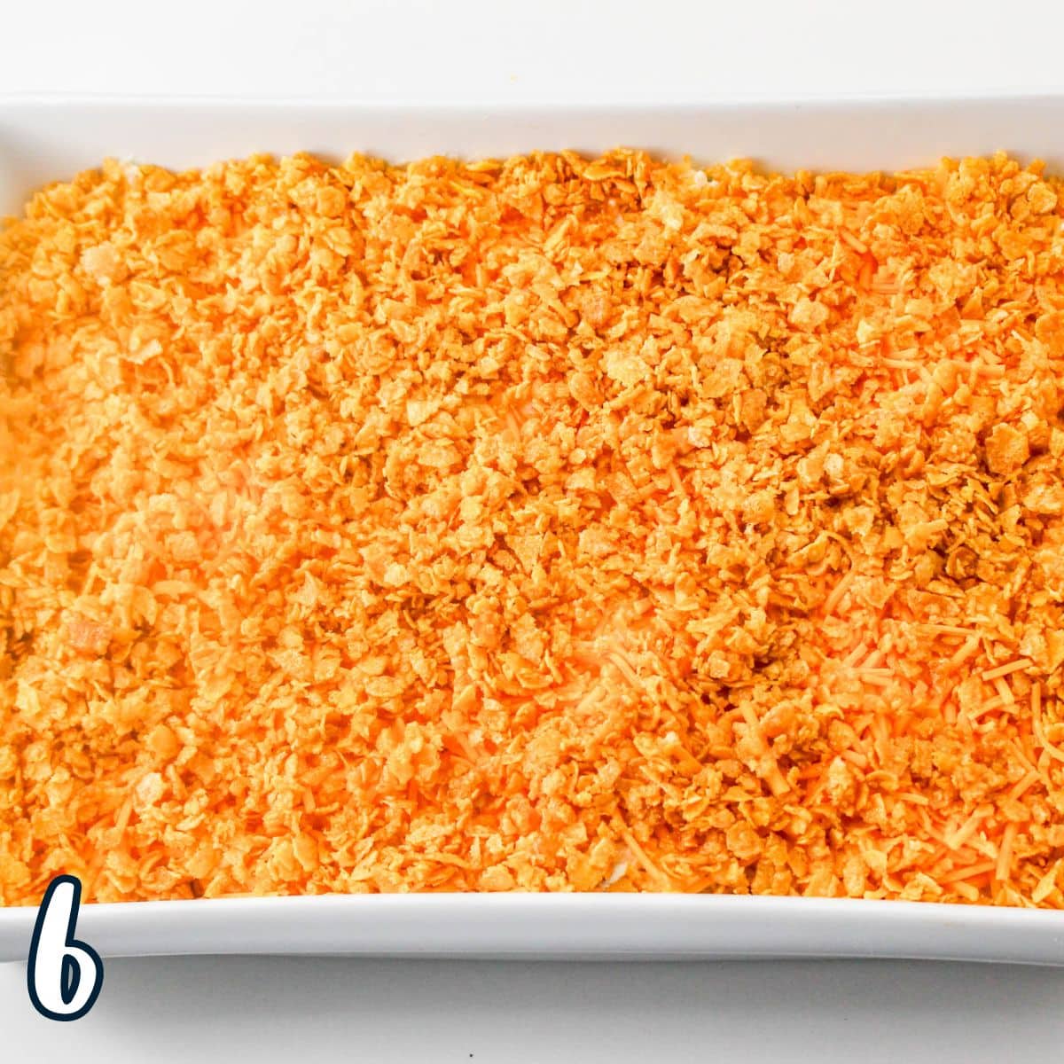 Buttery corn flakes sprinkled on top of hashbrown casserole in a baking dish. 