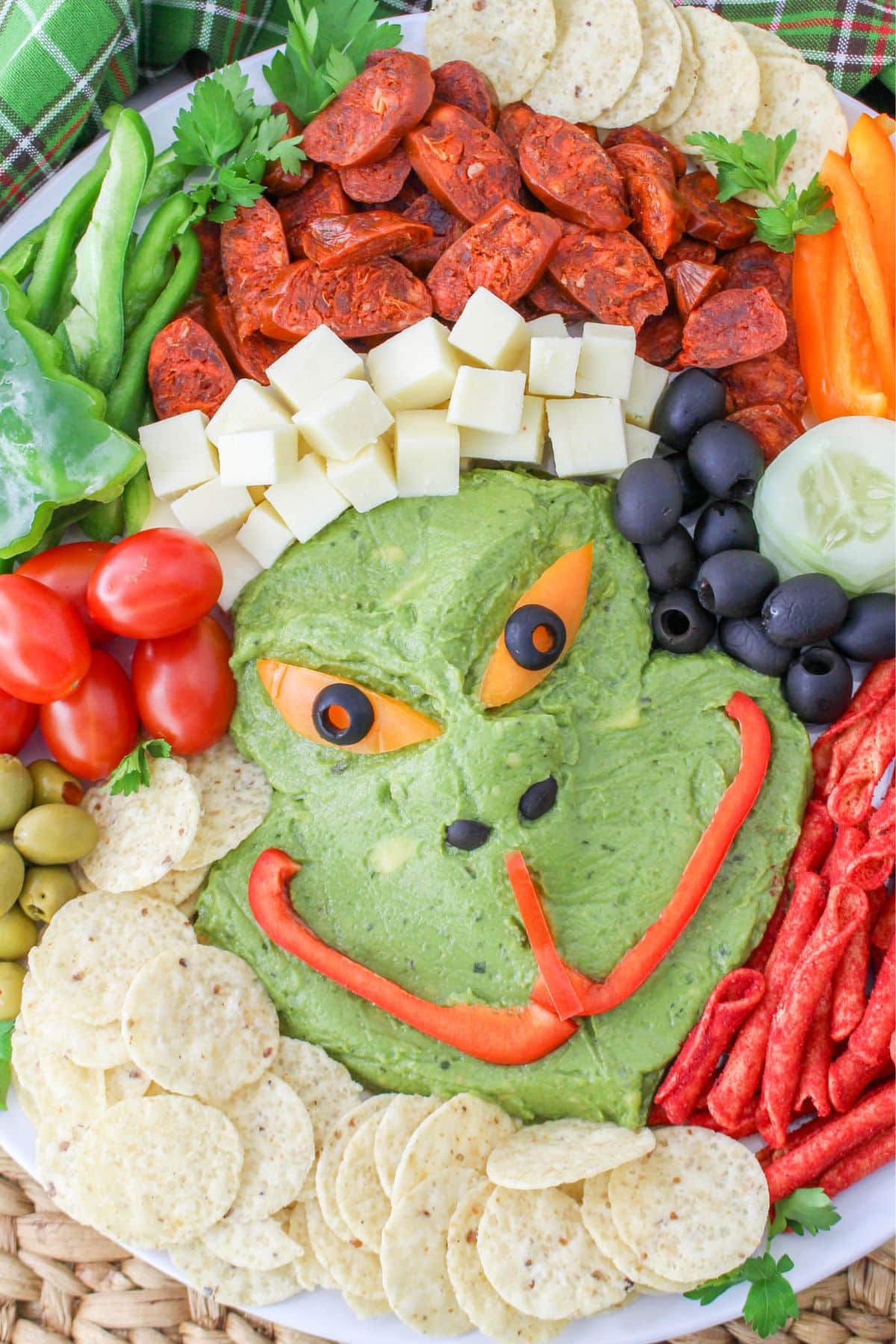 A plate with a grinch shaped guacamole and chips.