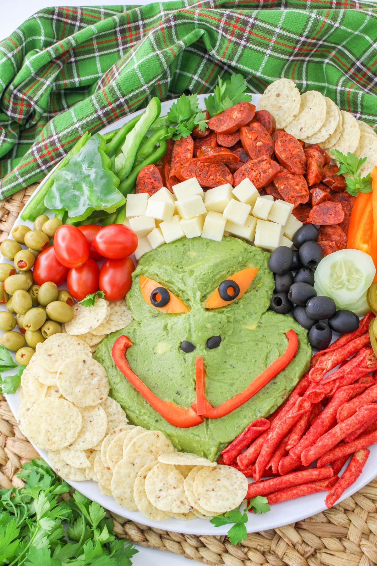 A plate with a grinch shaped guacamole and vegetables.