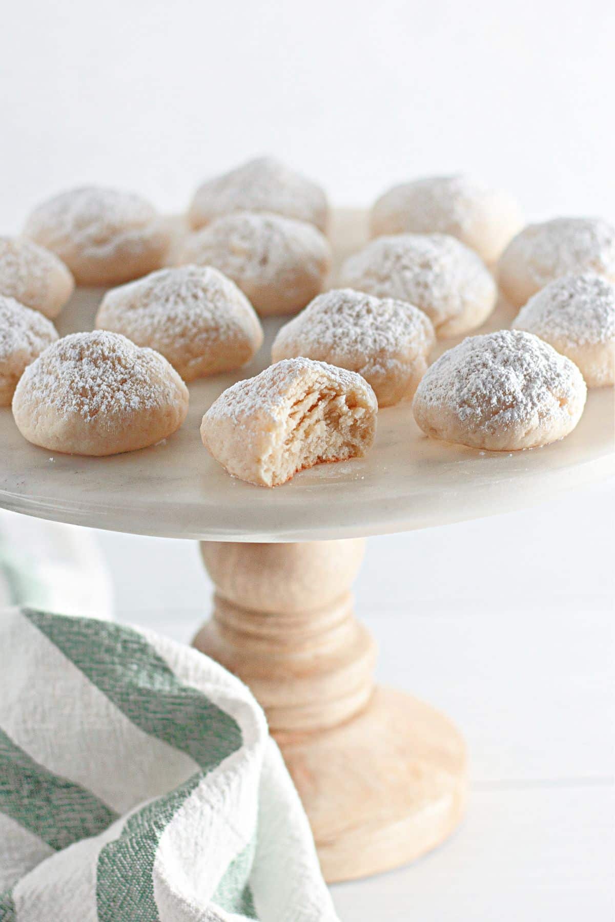 Powdered sugar cream cheese cookies on a cake stand.