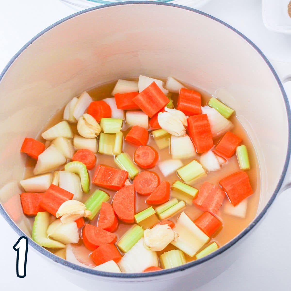 A pot filled with broth, carrots and celery.
