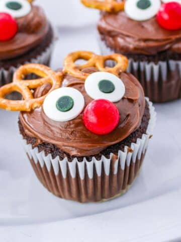 Chocolate reindeer cupcakes with pretzels on a plate.