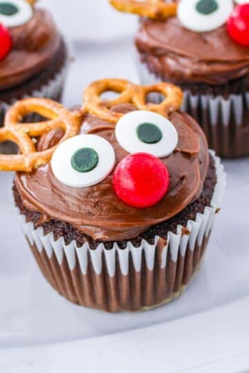 Chocolate reindeer cupcakes with pretzels on a plate.