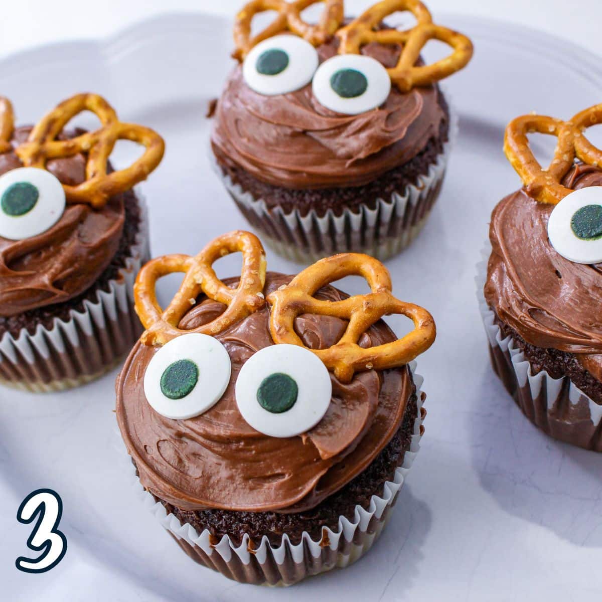 Reindeer cupcakes with pretzel antlers and eyes.