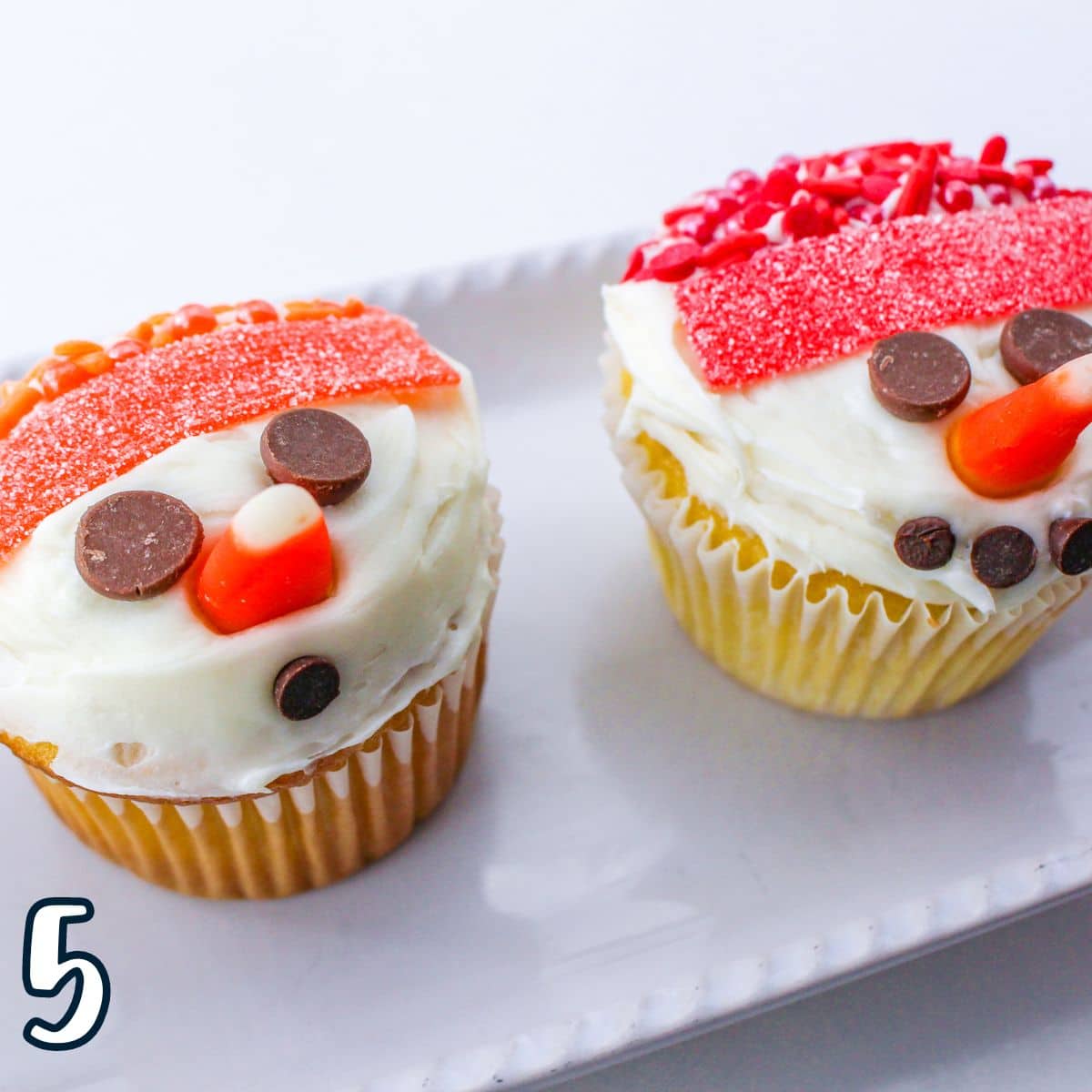Two snowman cupcakes on a white plate.