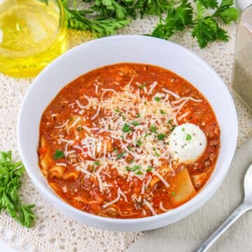 A bowl of tomato soup with parmesan cheese and parsley.