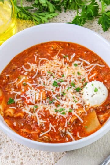 A bowl of tomato soup with parmesan cheese and parsley.