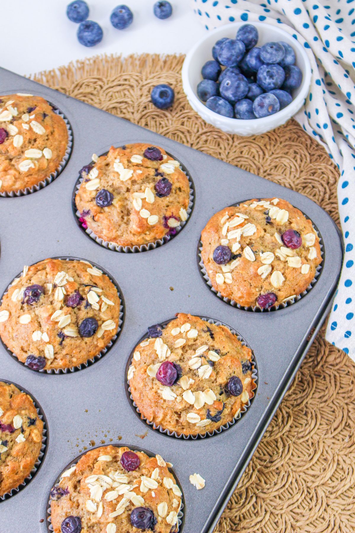 Blueberry muffins in a muffin tin with blueberries.