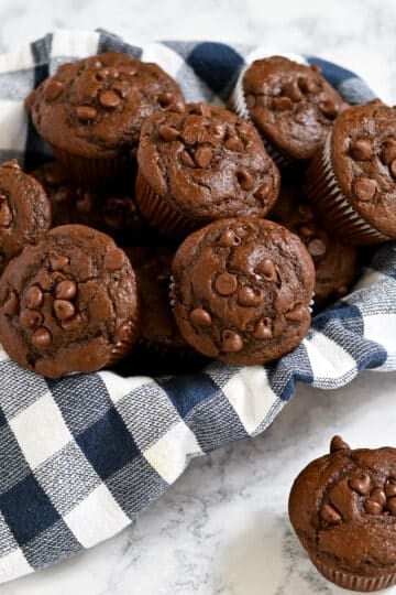 Chocolate Espresso Muffins with chocolate chips in a basket lined with a blue and white checkered cloth.