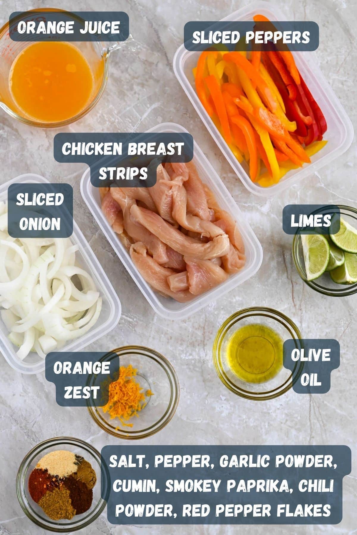 Various ingredients for a recipe displayed, including chicken breast strips, sliced peppers, onions, limes, spices, orange juice, orange zest, and olive oil.