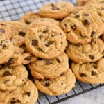 A pile of the Best Chocolate Chip Cookies cools on a wire rack.