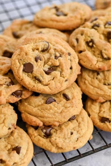 A pile of the Best Chocolate Chip Cookies cools on a wire rack.