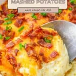 A spoon scoops creamy twice baked mashed potatoes, piled high with melted cheese, crispy bacon, and chopped green onions.