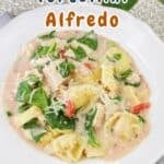 A plate of Chicken and Tortellini Alfredo with spinach and tomatoes, garnished with grated cheese. Text: "Chicken & Tortellini Alfredo.