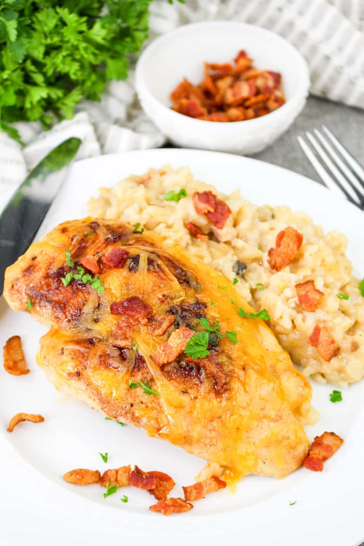 Cheesy chicken breast with bacon on a plate, served with creamy rice.