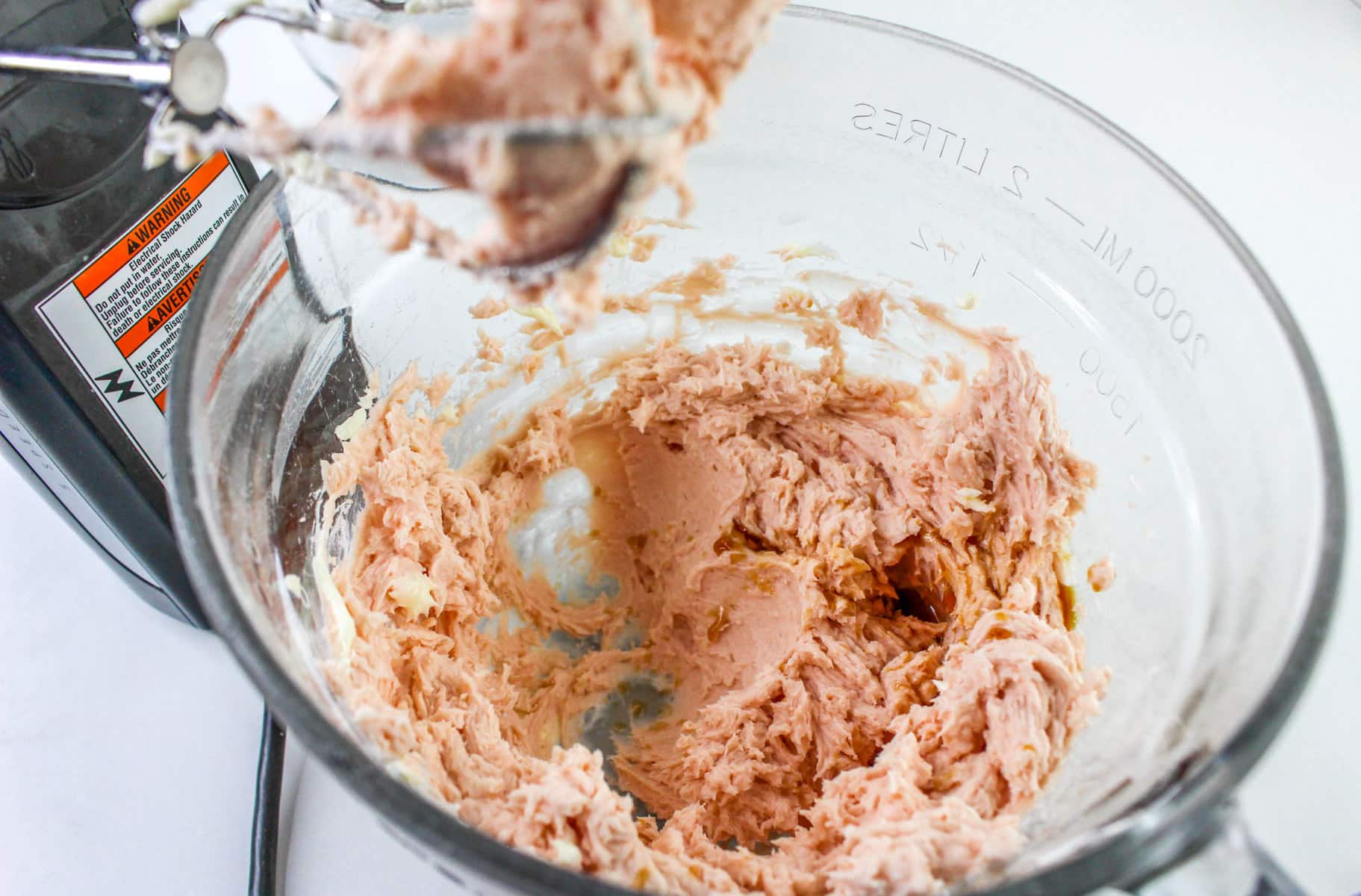 A mixing bowl with pink strawberry frosting.