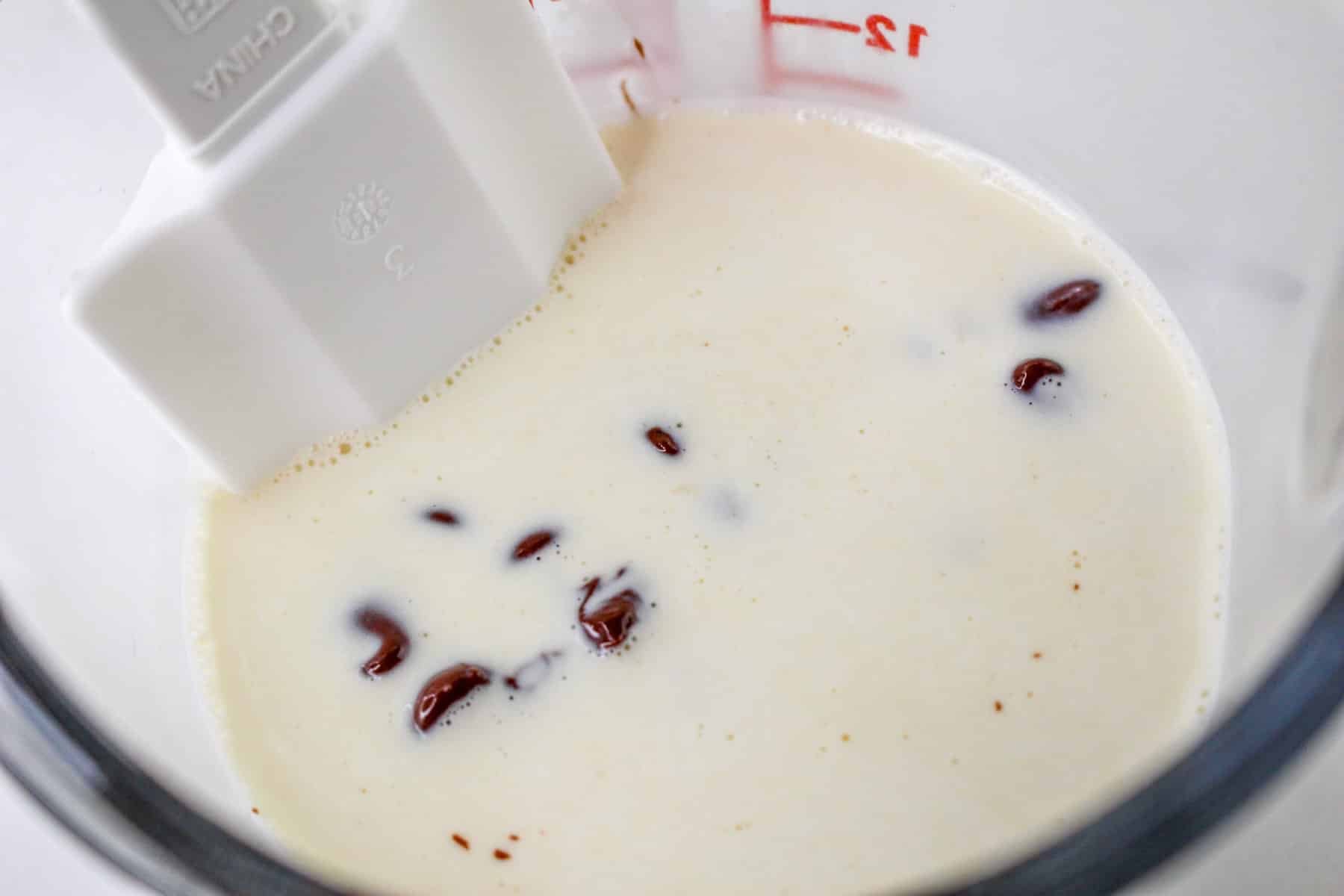 Chocolate Chips in a glass measuring cup with warm cream poured over. 