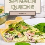 A slice of ham and spinach quiche rests on a plate, garnished with fresh spinach leaves for a delicious and inviting presentation.
