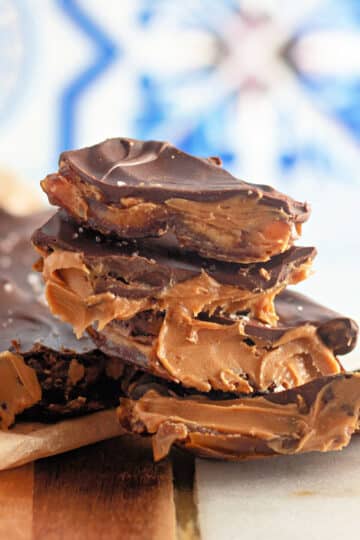 Stack of chocolate bark with peanut butter filling on a wooden and marble surface.