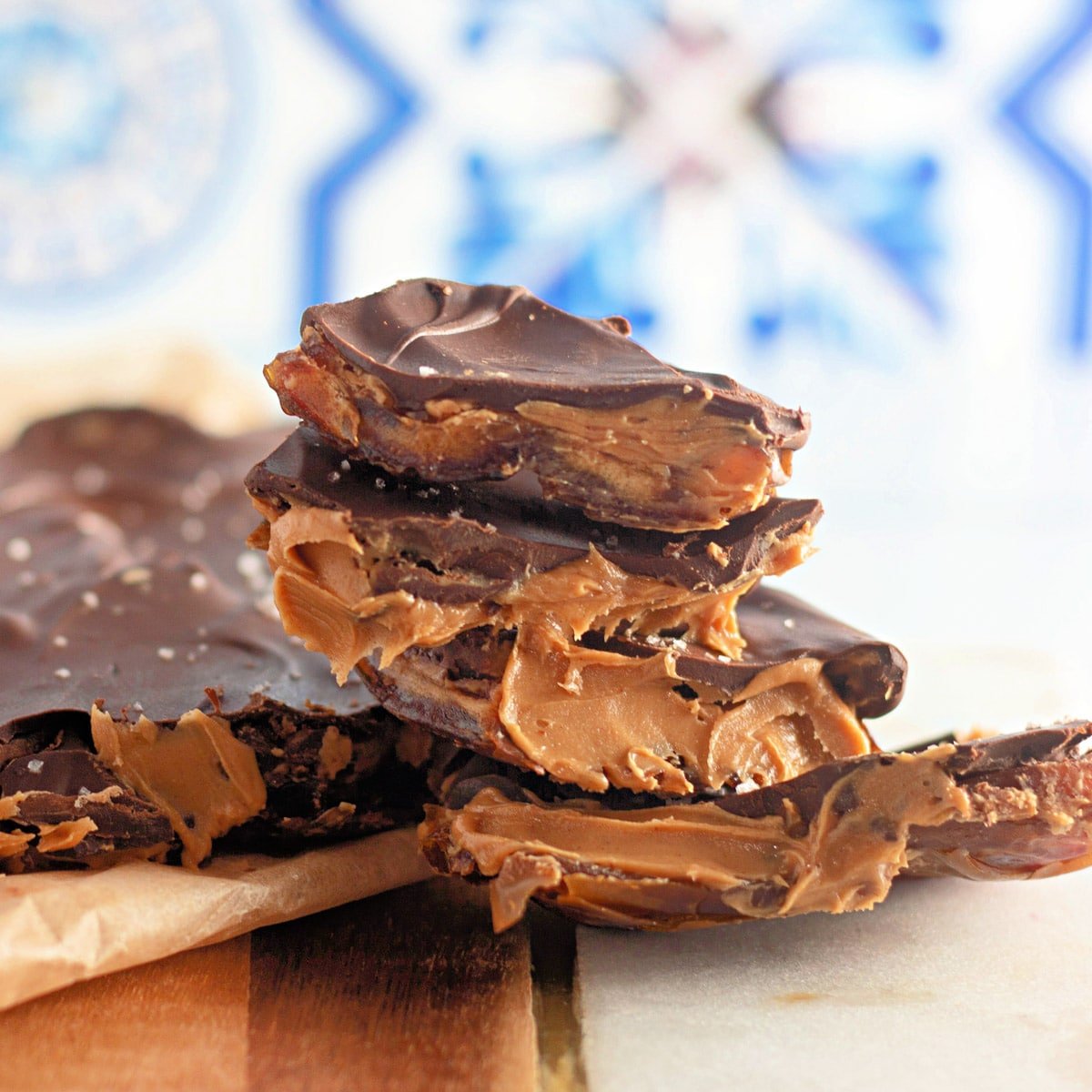 Stack of chocolate bark with peanut butter filling on a wooden and marble surface.