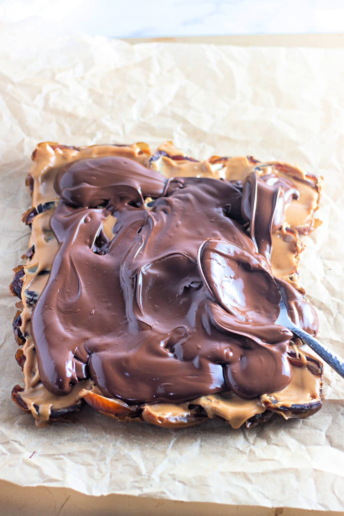 Chocolate and peanut butter spread over matzo on parchment paper.