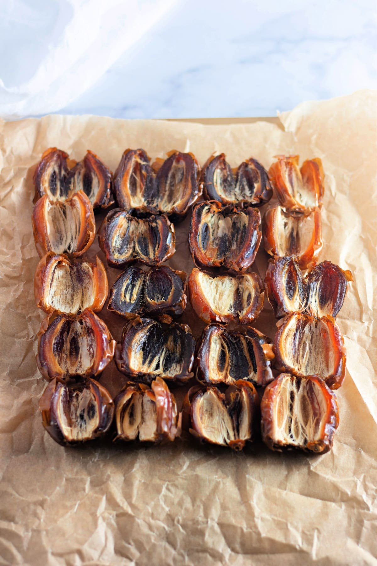 Square arrangement of halved dates on brown parchment paper.