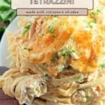 Plate of easy chicken tetrazzini with creamy sauce and melted cheese on top, garnished with herbs, on a wooden table.