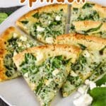 Indulge in a delicious spinach feta pizza, featuring perfectly sliced spinach and feta on a plate, topped with fresh spinach leaves and gooey cheese.
