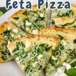 Slices of delectable spinach feta pizza rest on a white plate, perfectly garnished with vibrant fresh spinach leaves.