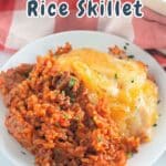 A delicious taco rice skillet topped with golden, melted cheese sits invitingly on a white dish.