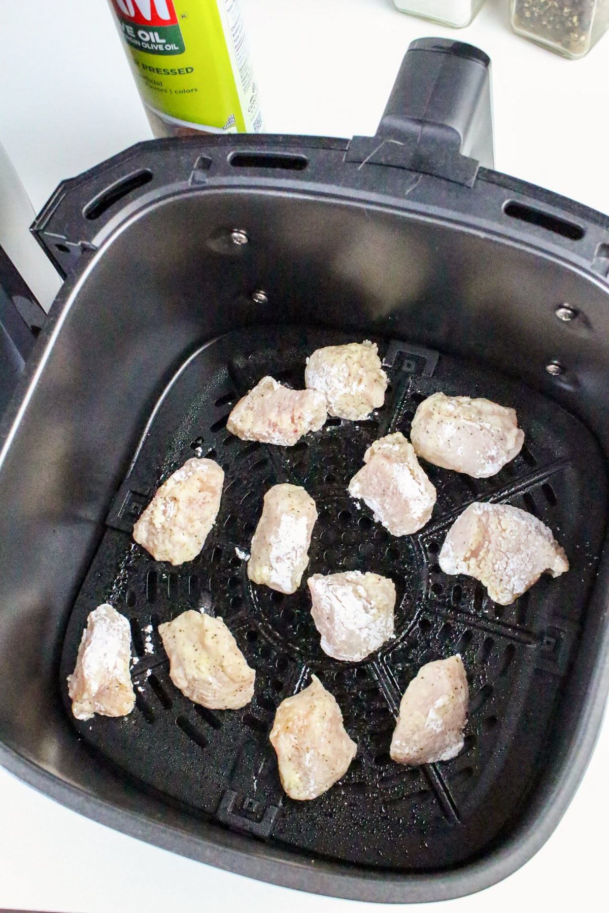 Raw chicken pieces in an air fryer basket, ready for cooking.