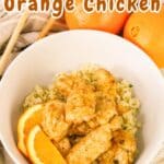 Bowl of air fryer orange chicken on rice, garnished with orange slices. Background shows whole oranges and chopsticks.