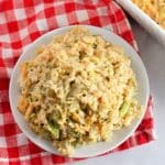 A plate of creamy rice and vegetable casserole on a red and white checkered cloth.