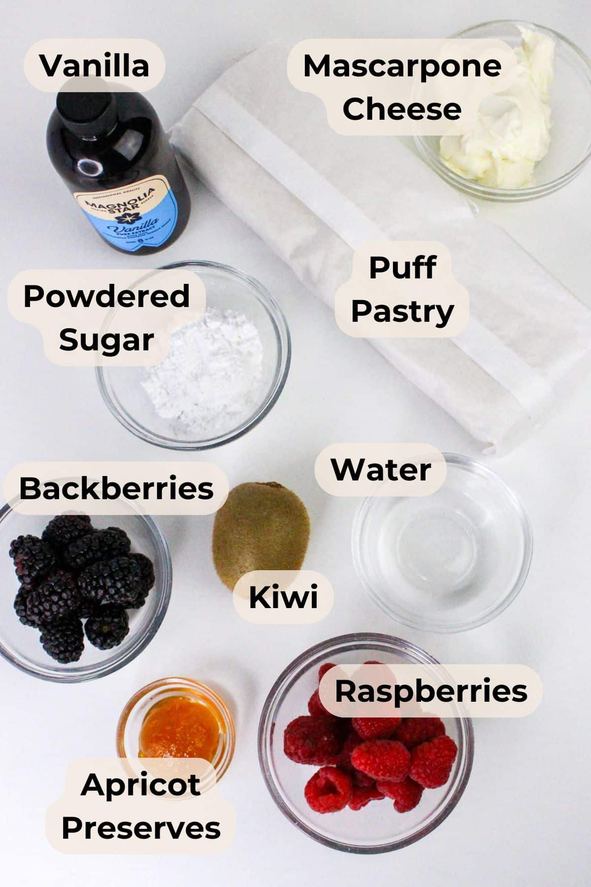 Labeled baking ingredients for a Puff Pastry Fruit Tart, including vanilla, mascarpone, puff pastry, berries, apricot preserves, and more.