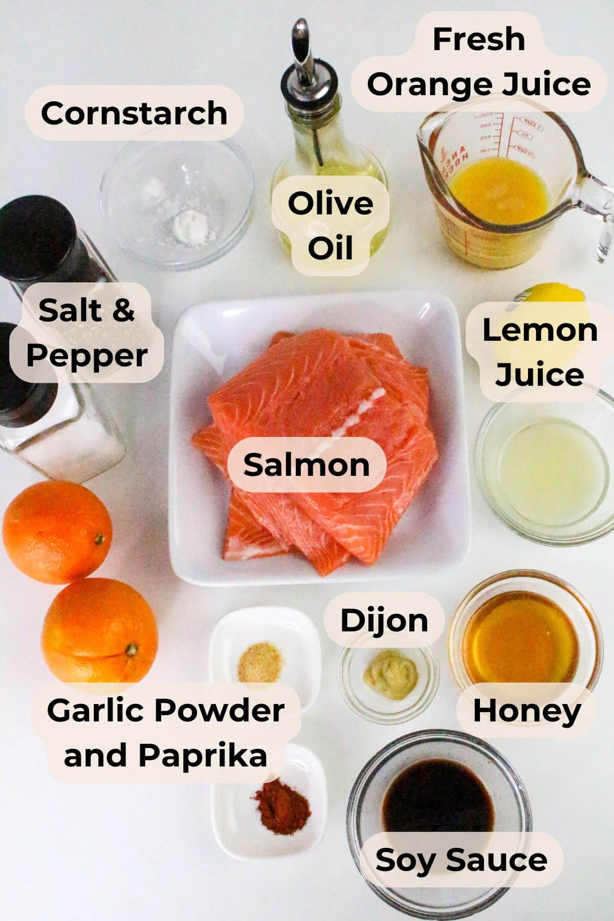 Top-down view of orange glazed salmon with ingredients for marinade, including orange juice, soy sauce, honey, spices, and oils.