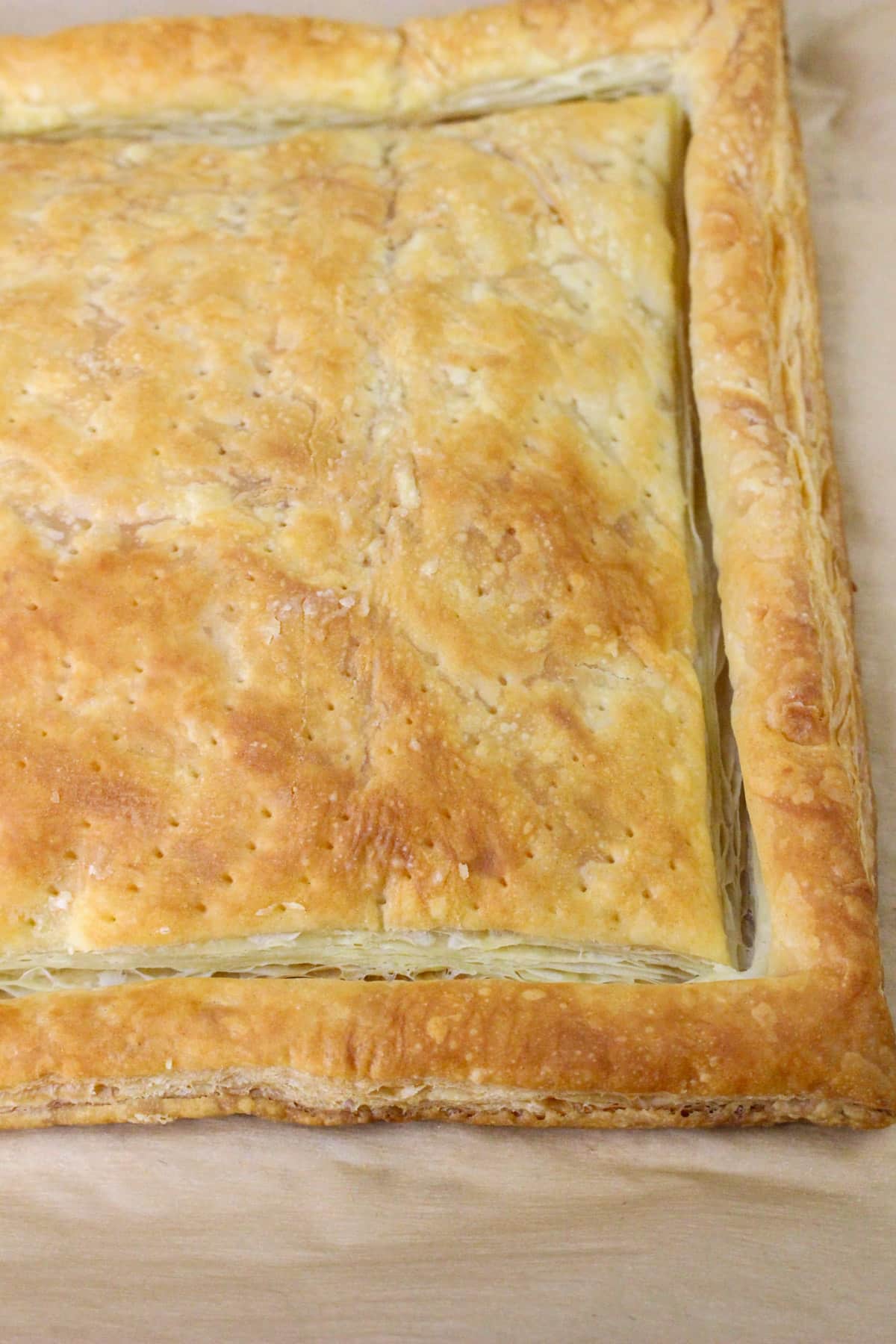 Golden-brown baked puff pastry with a rectangular shape on parchment paper.