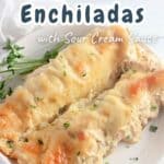 A plate featuring two Chicken Enchiladas with Sour Cream Sauce, elegantly garnished with a sprinkle of parsley, invitingly awaits your indulgence.