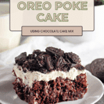A slice of Oreo Poke Cake with whipped topping and crushed Oreos sits on a white plate.